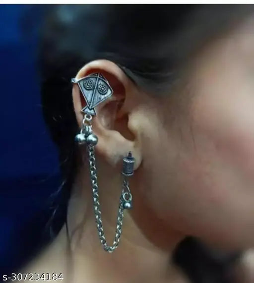 Close-up of an ear with a silver earring featuring a chain and spherical elements.